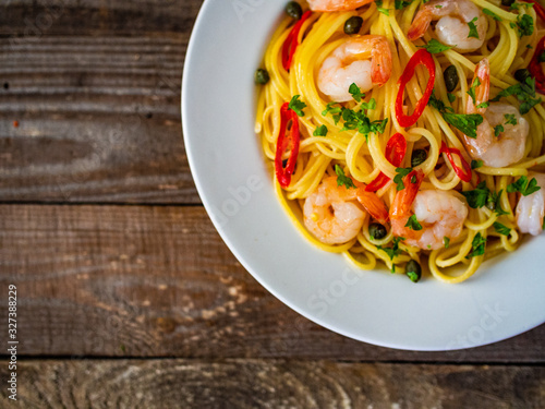 Pasta with prawns and vegetables on wooden background