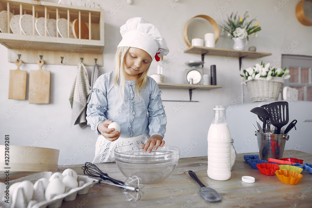 Child in a kitchen. Little girl with a dough. Kid in a blue shirt and white shef hat Child in a kitchen. Little girl with a dough. Kid in a blue shirt and white shef hat