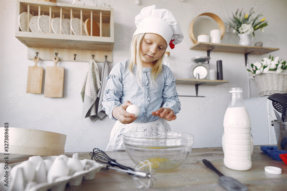 Child in a kitchen. Little girl with a dough. Kid in a blue shirt and white shef hat Child in a kitchen. Little girl with a dough. Kid in a blue shirt and white shef hat