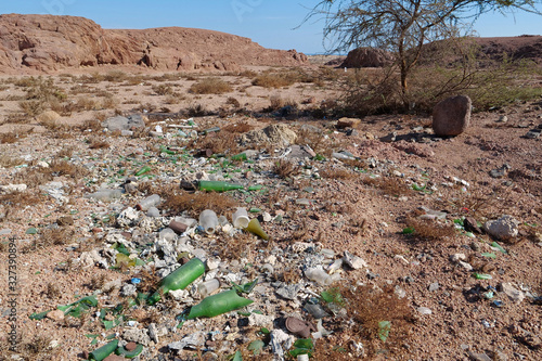 Broken bottles glass lies in desert, abuse of environment photo