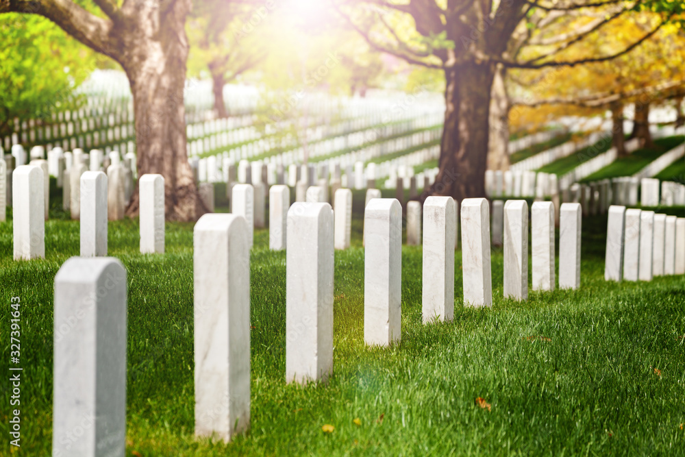 View or rows of white tombstones on the cemetery lit with warm sunlight sun