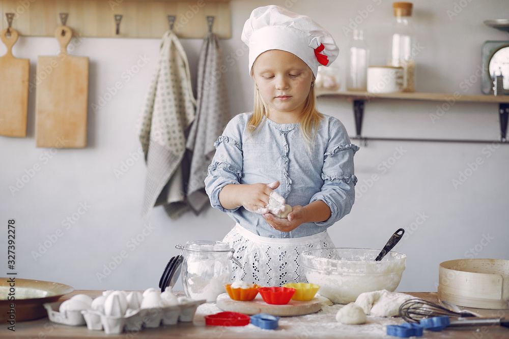 Child in a kitchen. Little girl with a dough. Kid in a blue shirt and white shef hat. Girl with cupcake shape. Child in a kitchen. Little girl with a dough. Kid in a blue shirt and white shef hat. Girl with cupcake shape.