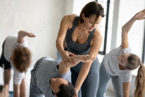 Yoga trainer helping to man do right Extended Side Angle © fizkes