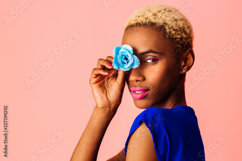 Portrait of  a beautiful young woman covering eye with blue rose flower, with trendy fresh makeup of pink lips and eyeliner photo