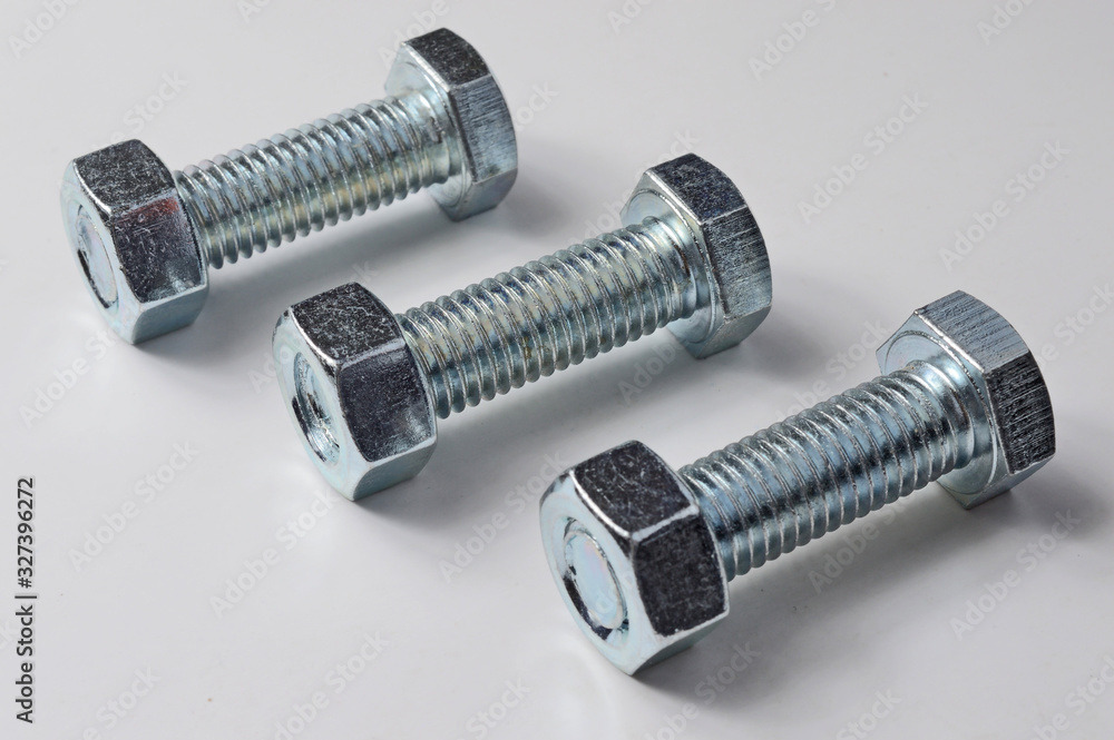 three bolts with nuts screwed on them. White background. three bolts with nuts screwed on them. White background.