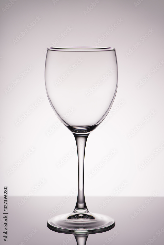 Vertical full size photo of clean transparent with glares wine glass isolated on gray white background with gradient