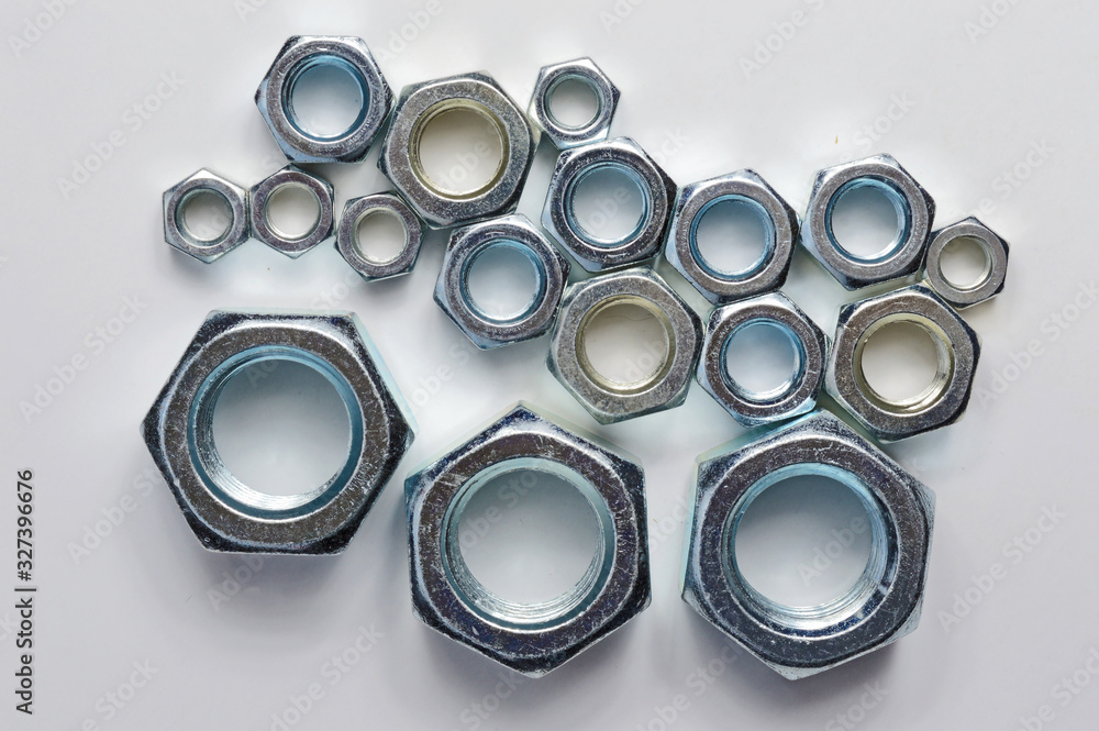 New chrome screw-nut of different sizes on a white background. Concept. New chrome screw-nut of different sizes on a white background. Concept.