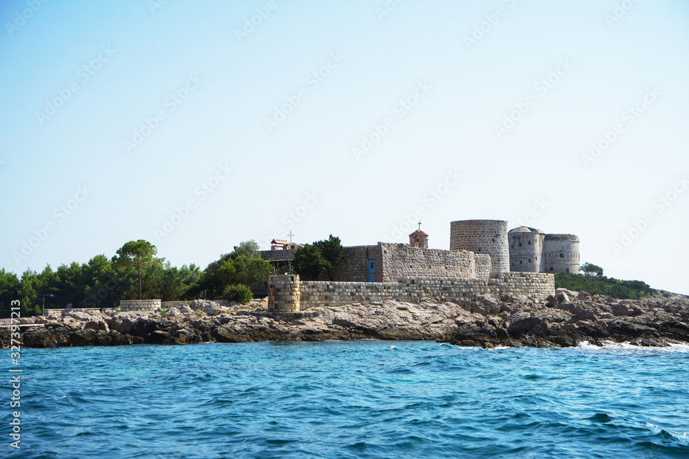 A small stone fortress on the rocky coast of the Bay of Kotor in summer day. Montenegro, Adriatic Sea.