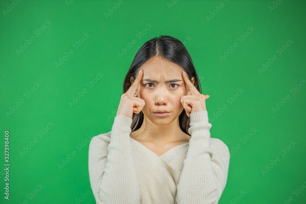 Serious thought of a young Asian woman on a green background Serious thought of a young Asian woman on a green background