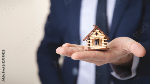 business man hand wooden house model
