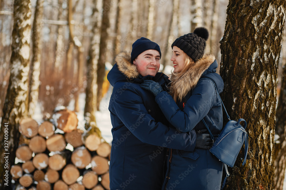 Elegant couple standing in a winter forest. Man and woman near trees Elegant couple standing in a winter forest. Man and woman near trees