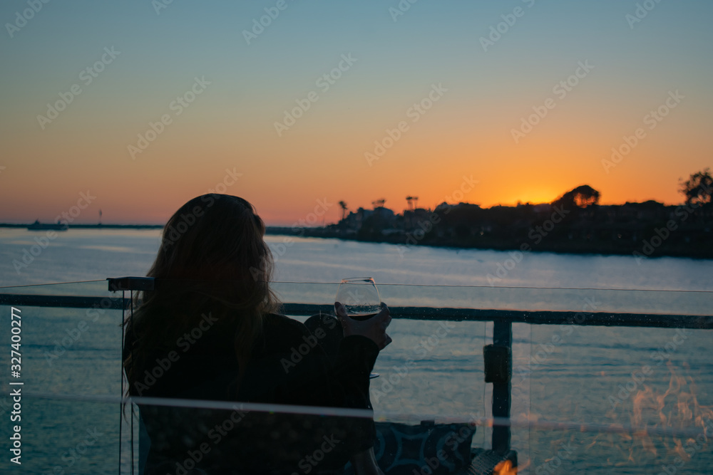 Young Woman enjoying sunset in Marina del Rey in Winter with fire pit