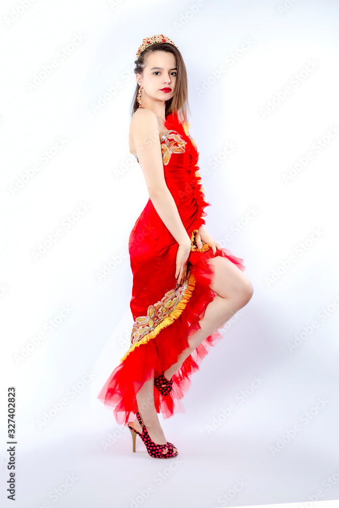 Fashion photo of a beautiful elegant brunette woman in a carnival sexy red dress, high heels posing over gray background. Christmas carnival photo. Isolate Fashion photo of a beautiful elegant brunette woman in a carnival sexy red dress, high heels posing over gray background. Christmas carnival photo. Isolate