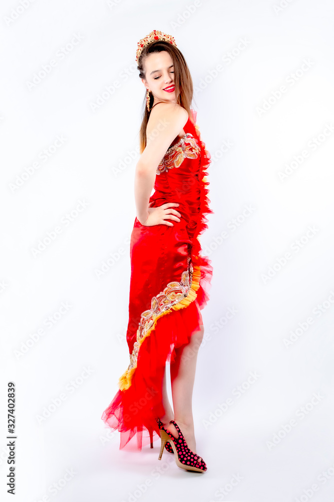 Fashion photo of a beautiful elegant brunette woman in a carnival sexy red dress, high heels posing over gray background. Christmas carnival photo. Isolate Fashion photo of a beautiful elegant brunette woman in a carnival sexy red dress, high heels posing over gray background. Christmas carnival photo. Isolate