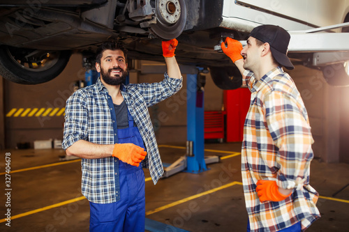 portrait of smiling automechanics in workwear standing in the auto service stationand looking at the camera photo