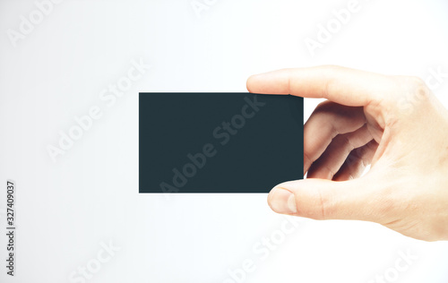 Hand holding a blank black business card.