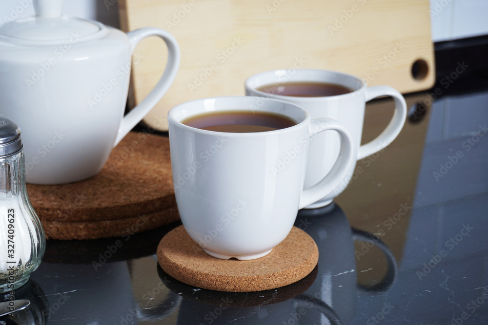 Fototapeta premium Kitchen interier. Brewed tea in white mugs on the kitchen table. Comfort and warmth at home. Tea party