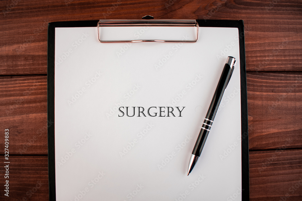 Word surgery: text written on a shit of paper of notebook on the wooden background. Medical concept. Word surgery: text written on a shit of paper of notebook on the wooden background. Medical concept.