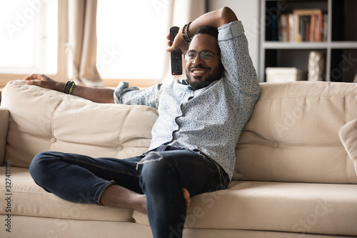 Schilderij op canvas Happy handsome young african ethnicity man watching television programs