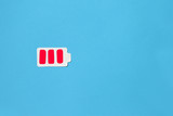 Battery low concept. Battery paper figure and red blocks with copyspace, top view, flat lay. on a blue background