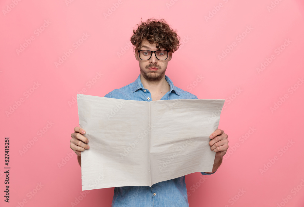 young casual guy reading newspaper - obrazy, fototapety, plakaty 