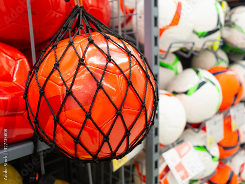 Orange soccer ball new in the sports store, against the background of other colored balls. Sports concept