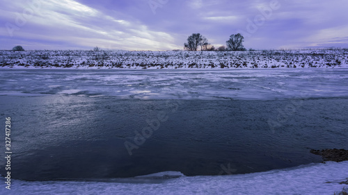 Winter landscape with frozen river and trees in the snow