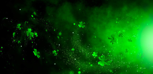 St. Patrick's Day abstract green background decorated with shamrock leaves. Patrick Day pub party celebrating. Abstract Border art design magic backdrop. Widescreen clovers on black with copy space