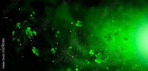 St. Patrick's Day abstract green background decorated with shamrock leaves. Patrick Day pub party celebrating. Abstract Border art design magic backdrop. Widescreen clovers on black with copy space photo