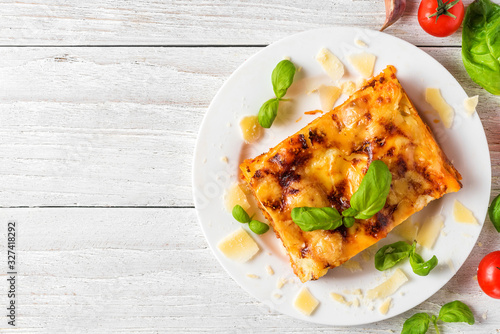 Konstfotografi Homemade meat lasagna with fresh basil and parmesan cheese in a plate on white wooden table