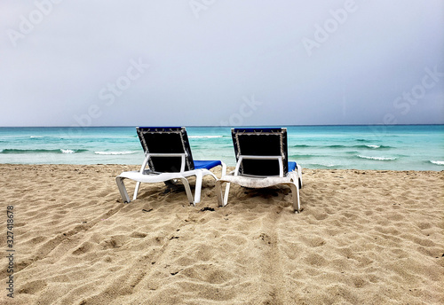 Fototapeta Naklejka Na Ścianę i Meble -  Two loungers, chaise-longues on a cuban beach before storm