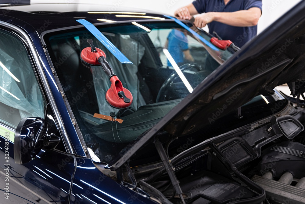 Service workers replacing car front windshield.