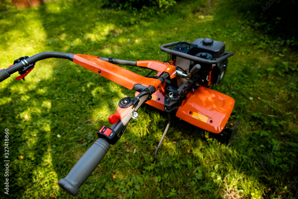 garden with tiller machine. Garden tiller to work, close up.Abstract and conceptual of motor hoe at work. garden with rototiller , tiller tractor, cutivator, miiling machine. Man plowing the garden garden with tiller machine. Garden tiller to work, close up.Abstract and conceptual of motor hoe at work. garden with rototiller , tiller tractor, cutivator, miiling machine. Man plowing the garden