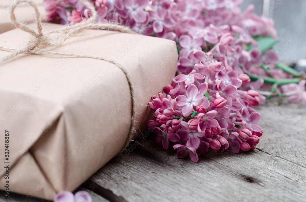 Handmade gift boxes wrapped with craft brown paper, decorated with fresh purple lilac flowers on a vintage wooden surface. Handmade gift boxes wrapped with craft brown paper, decorated with fresh purple lilac flowers on a vintage wooden surface.