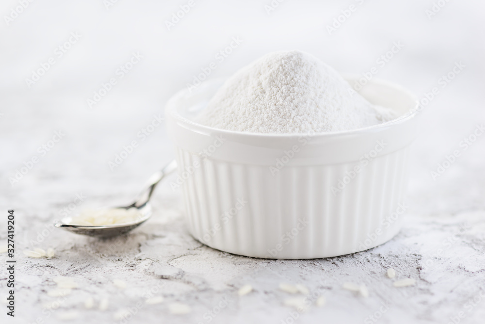 Rice flour with a heap in a white bowl on the table. Gluten free, healthy diet concept. Rice flour with a heap in a white bowl on the table. Gluten free, healthy diet concept.