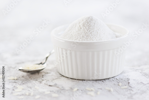 Rice flour with a heap in a white bowl on the table. Gluten free, healthy diet concept.