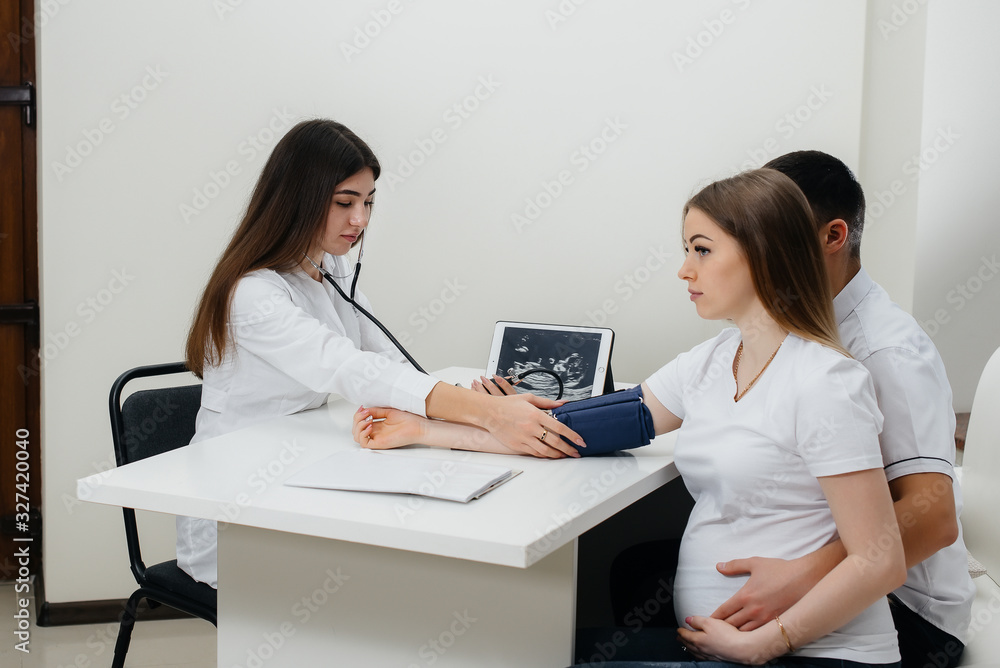 A young couple at a gynecologist's consultation after an ultrasound. Pregnancy, and health care A young couple at a gynecologist's consultation after an ultrasound. Pregnancy, and health care