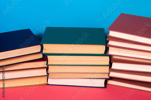 Piles of books on a pink and blue background.