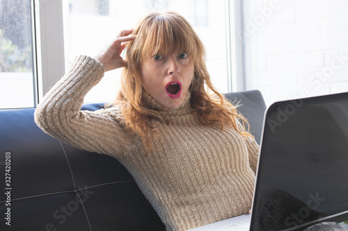 adult woman with laptop and expression of surprise or amazement