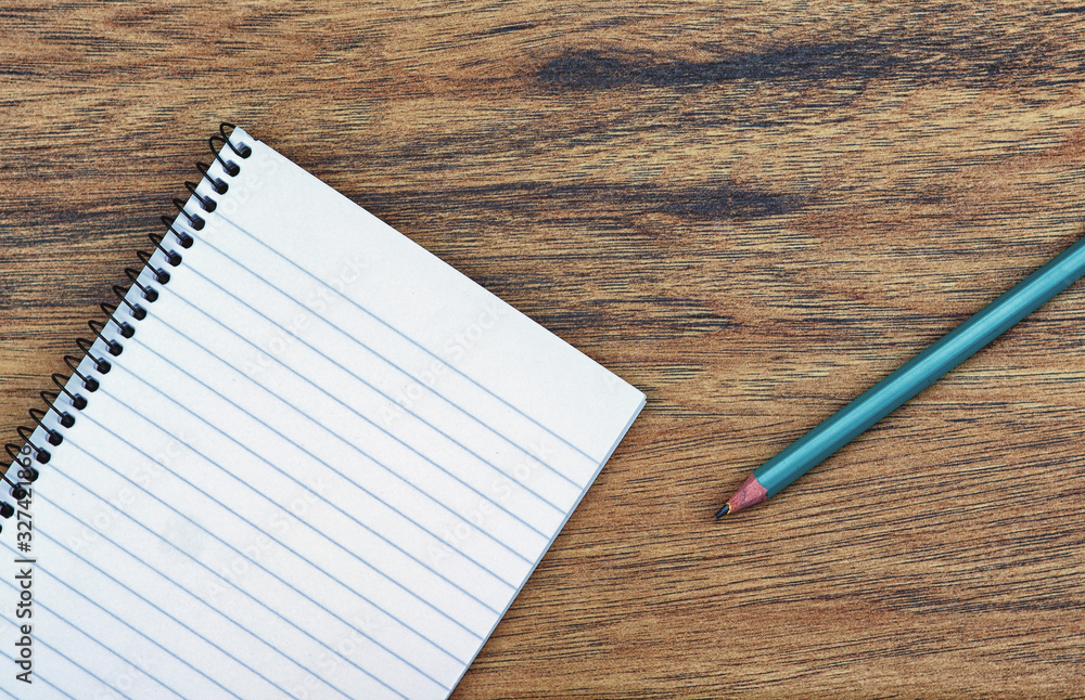 Overhead photo of blank lined spiral bound notebook with green pencil Overhead photo of blank lined spiral bound notebook with green pencil