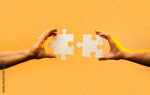 Closeup hand of connecting jigsaw puzzle. Business solutions, success and strategy concept. Two hands trying to connect couple puzzle piece on yellow background. Holding puzzle. Teamwork concept