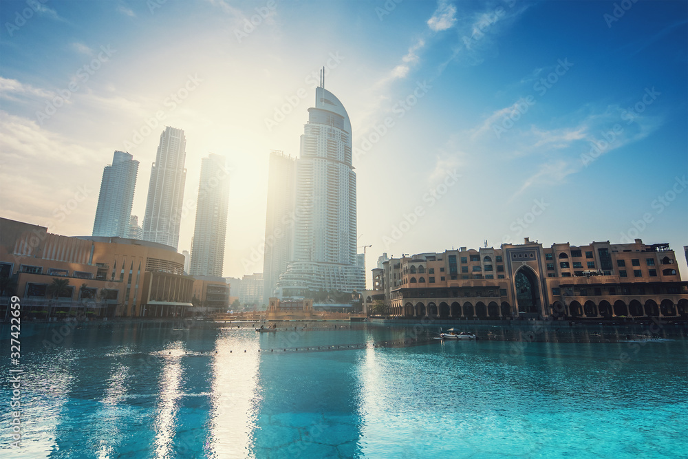 Downtown Dubai district with high rise buildings in sunrise sunlight and pool. United Arab Emirates, UAE.