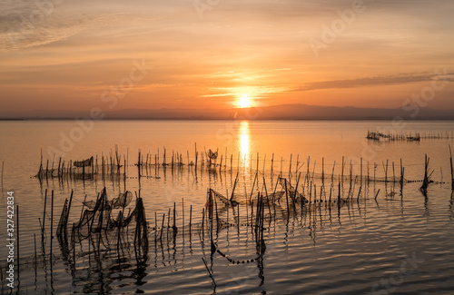 Sunset pier Albufera Valencia reflections orange sky in the lake Naural Park Spain. traditional fishing nets in the water photo