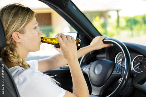 woman drinking from a beer bottle while driving car
