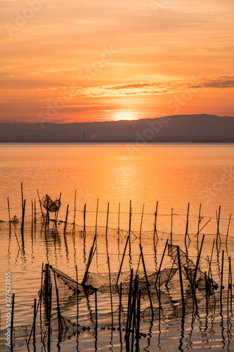 Sunset pier Albufera Valencia reflections orange sky in the lake Naural Park Spain. traditional fishing nets in the water photo