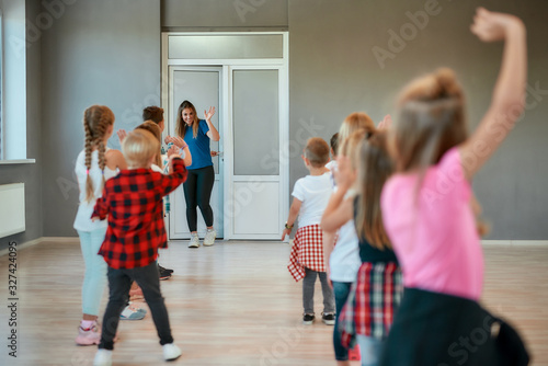 Saying hello. Group of children waving to dance teacher while standing in the dance studio. Choreography class.