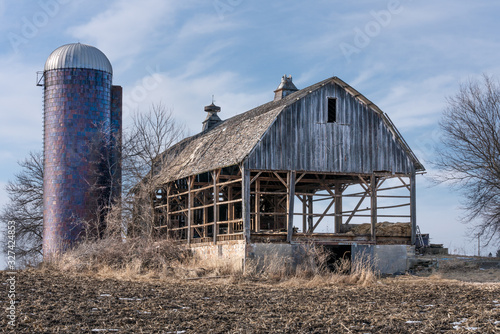 фотографія A large old wooden barn that is being taken apart, to salvage the barn siding