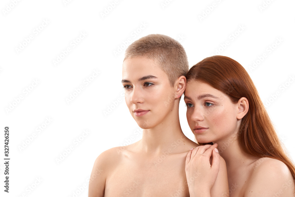 Two different girls. Beauty portrait of young blonde and redhead women looking away while posing naked against white background. Natural beauty Two different girls. Beauty portrait of young blonde and redhead women looking away while posing naked against white background. Natural beauty