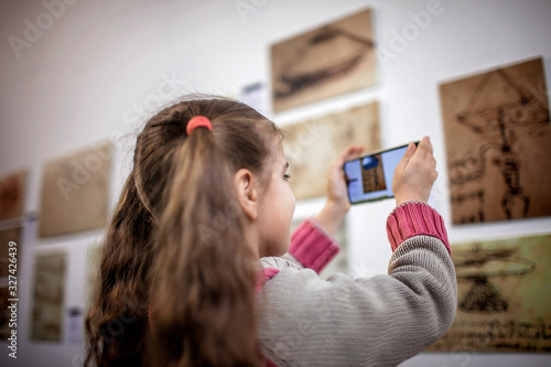 Curious girl exploring a contemporary art exhibition with augmented reality mobile application photo