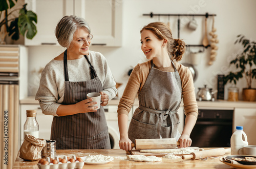 happy family grandmother  old mother mother-in-law and daughter-in-law daughter cook in kitchen, knead dough, bake cookies.